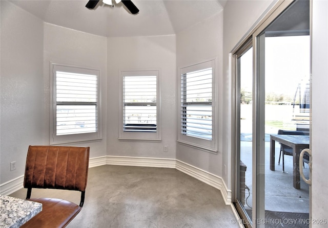 sitting room featuring a healthy amount of sunlight, baseboards, and concrete flooring