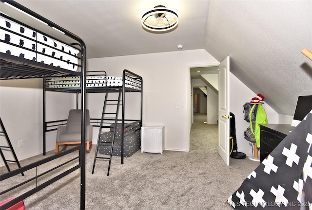 bedroom featuring lofted ceiling, carpet floors, and a textured ceiling