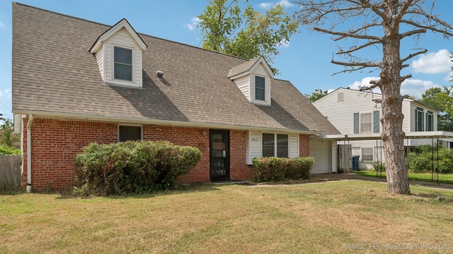 view of front of property featuring an attached garage, roof with shingles, a front yard, and brick siding