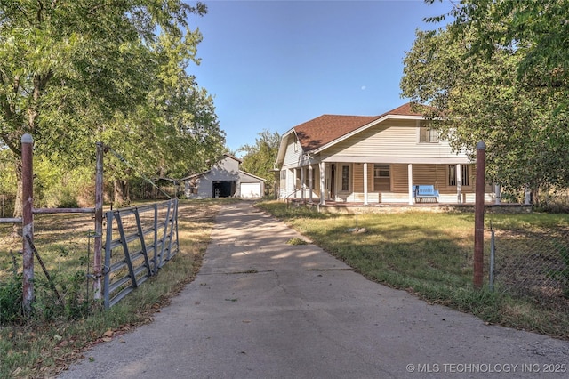 view of front of home featuring an outbuilding, covered porch, a front yard, fence, and a garage