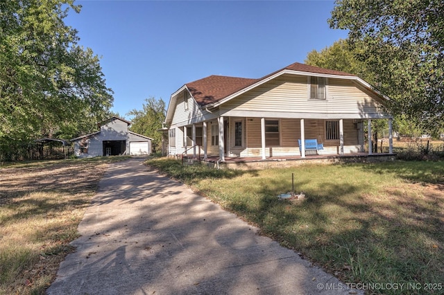 bungalow with covered porch, a front lawn, an outdoor structure, and a detached garage