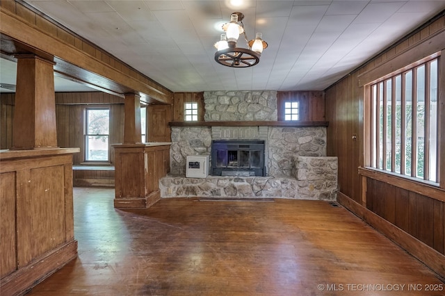 unfurnished living room featuring dark wood-style floors, wood walls, and a fireplace