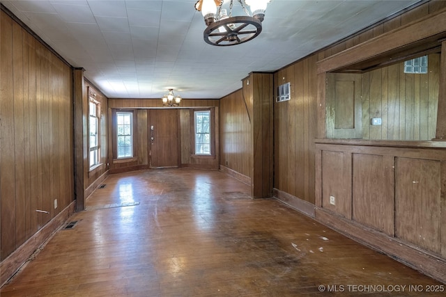 entryway with wooden walls, baseboards, visible vents, wood finished floors, and an inviting chandelier