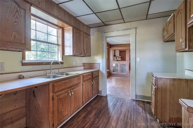 kitchen with dark wood-style flooring, light countertops, a sink, and a drop ceiling