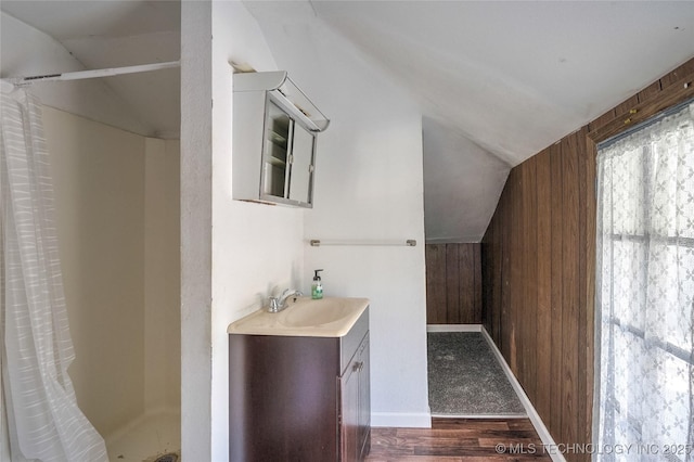 bathroom featuring lofted ceiling, a stall shower, wood walls, vanity, and wood finished floors