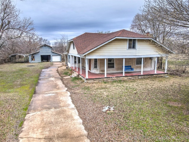 bungalow-style home with roof with shingles, a porch, a garage, an outdoor structure, and a front lawn