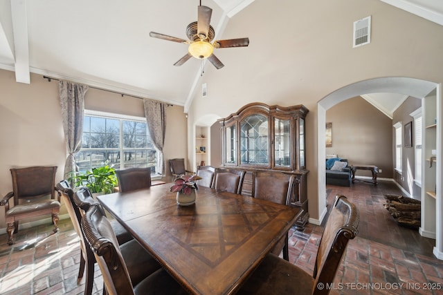 dining area featuring brick floor, arched walkways, ornamental molding, high vaulted ceiling, and baseboards