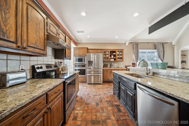 kitchen with tasteful backsplash, visible vents, stainless steel appliances, under cabinet range hood, and a sink