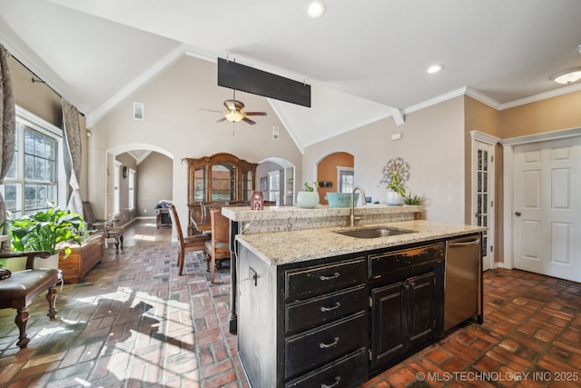 kitchen with brick floor, crown molding, stainless steel dishwasher, a kitchen island with sink, and a sink