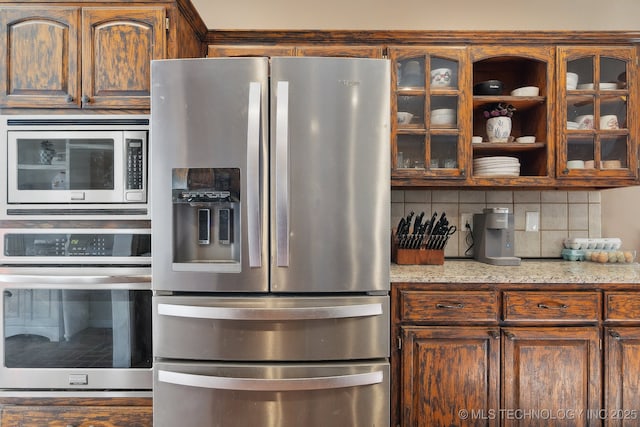 kitchen with stainless steel appliances, glass insert cabinets, backsplash, and light stone counters