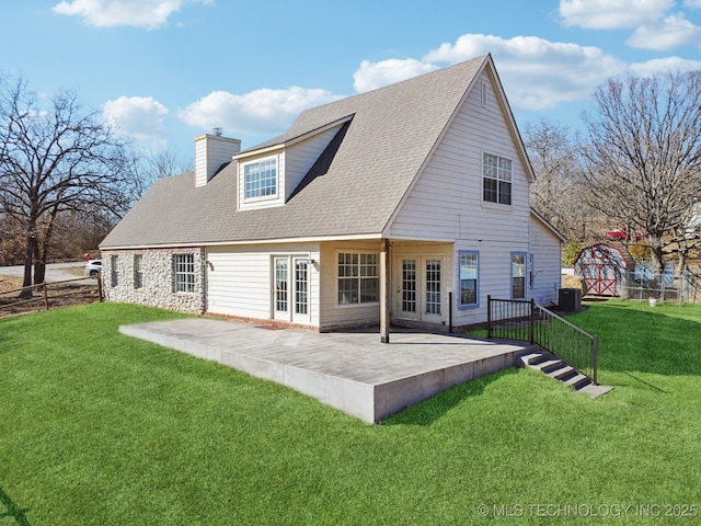 back of property with french doors, a chimney, central air condition unit, a lawn, and a patio area