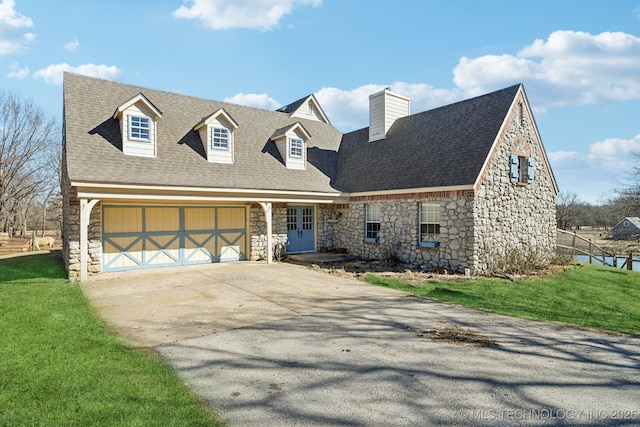 cape cod house with a garage, stone siding, driveway, a front lawn, and a chimney