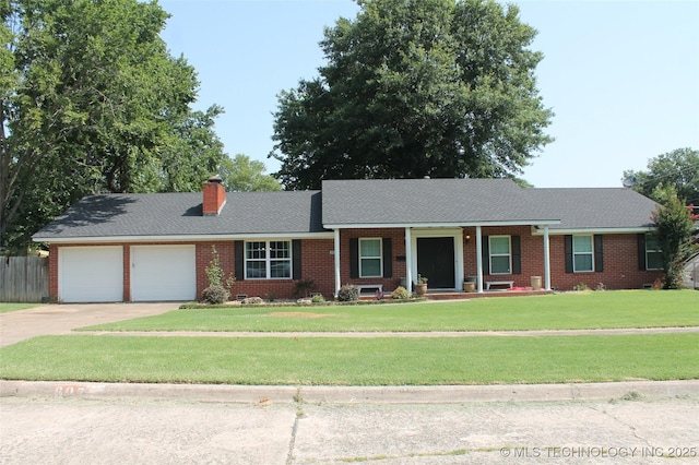 single story home with driveway, a chimney, an attached garage, a front lawn, and brick siding