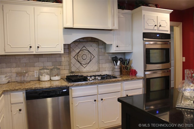 kitchen featuring tasteful backsplash, white cabinetry, stainless steel appliances, and light stone counters