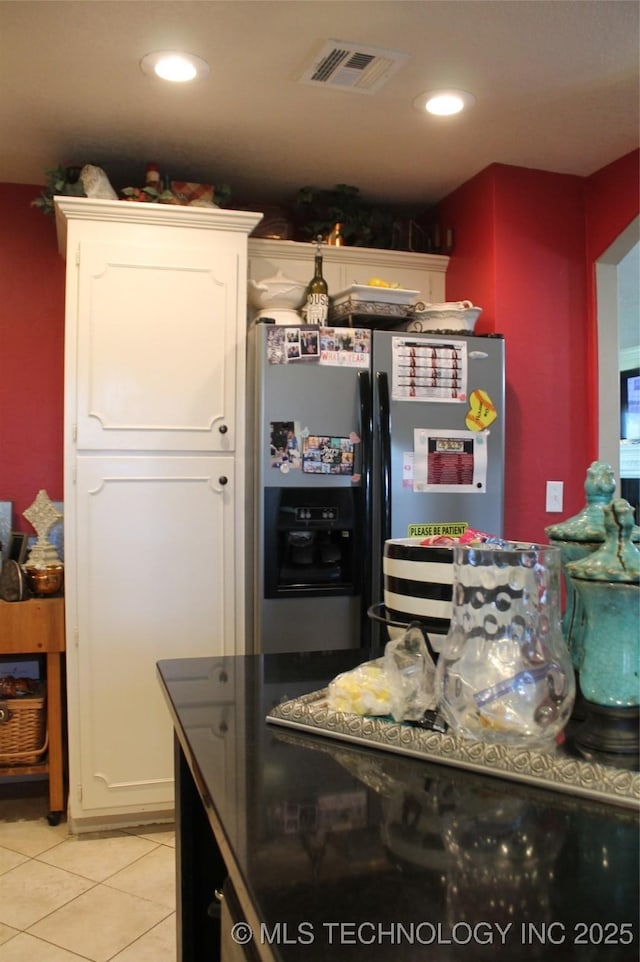 kitchen featuring light tile patterned floors, recessed lighting, black fridge with ice dispenser, visible vents, and white cabinets