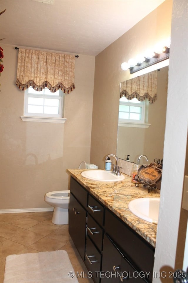 full bathroom with double vanity, a sink, toilet, and tile patterned floors