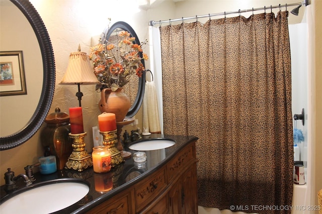 bathroom with double vanity, curtained shower, and a sink