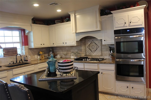 kitchen featuring a sink, visible vents, white cabinetry, appliances with stainless steel finishes, and backsplash