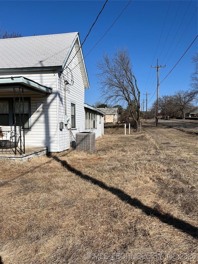 view of property exterior featuring central AC and roof with shingles