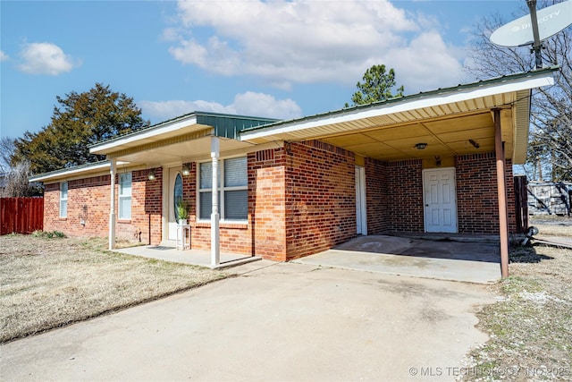 single story home featuring a carport, fence, concrete driveway, and brick siding