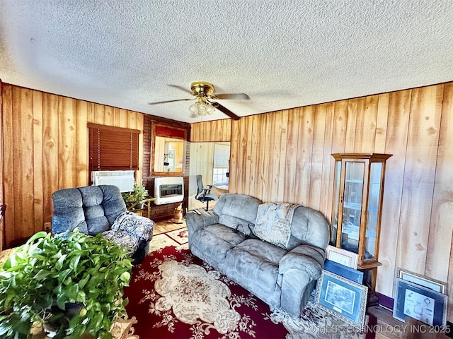 117 S Bluff Ave, Tahlequah, OK 74464 - living room featuring wooden walls, a ceiling fan, a textured ceiling, heating unit, and wood finished floors