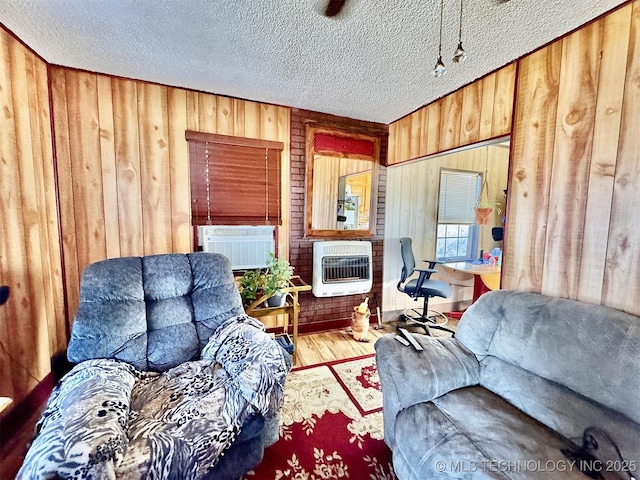 117 S Bluff Ave, Tahlequah, OK 74464 - living room with heating unit, wood walls, wood finished floors, a textured ceiling, and cooling unit