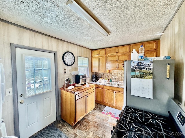 117 S Bluff Ave, Tahlequah, OK 74464 - kitchen featuring a sink, freestanding refrigerator, wood walls, light countertops, and range with gas cooktop