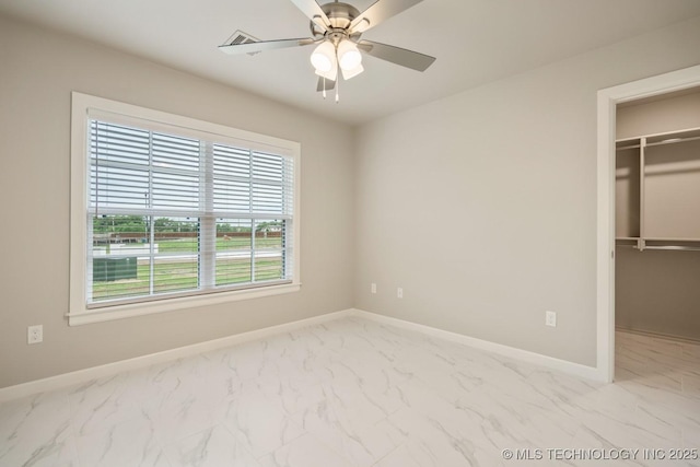 unfurnished bedroom featuring ceiling fan, baseboards, a closet, marble finish floor, and a spacious closet