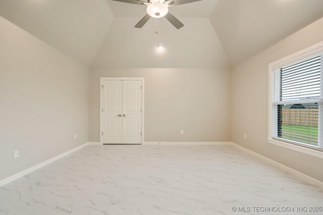 spare room featuring baseboards, ceiling fan, vaulted ceiling, and marble finish floor