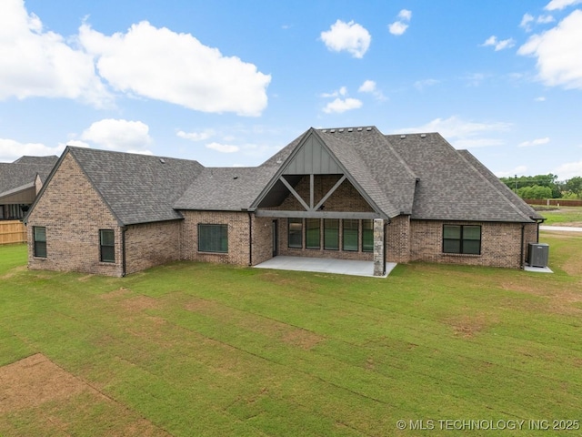 rear view of property with brick siding, a shingled roof, a patio area, and a yard