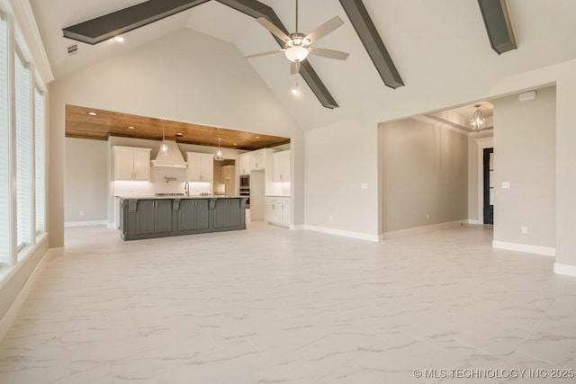 unfurnished living room featuring baseboards, marble finish floor, ceiling fan, and high vaulted ceiling
