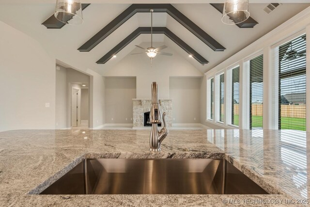 kitchen with visible vents, open floor plan, high vaulted ceiling, light stone counters, and a sink