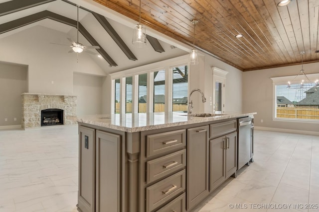 kitchen featuring ceiling fan, a kitchen island with sink, dishwasher, a sink, and light stone counters
