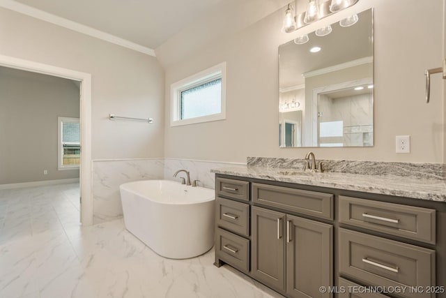 full bathroom with crown molding, vanity, marble finish floor, a freestanding tub, and a wainscoted wall