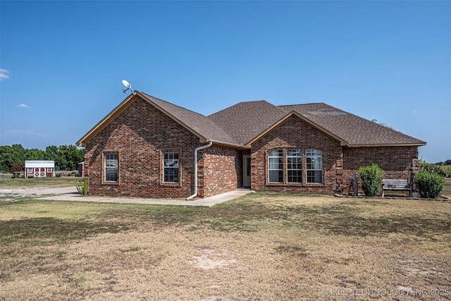 view of front facade with roof with shingles, a front lawn, and brick siding