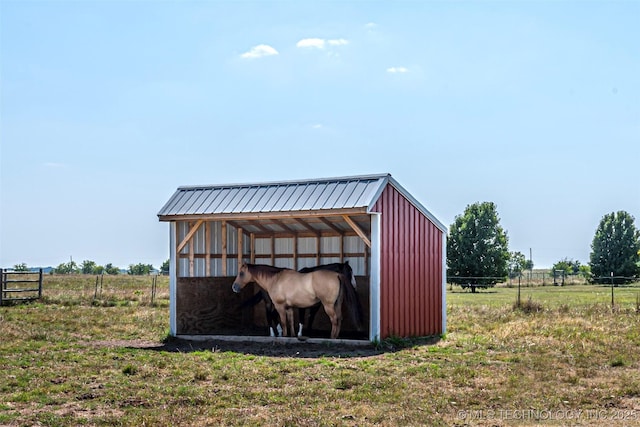 view of outbuilding with a rural view, fence, and an outdoor structure