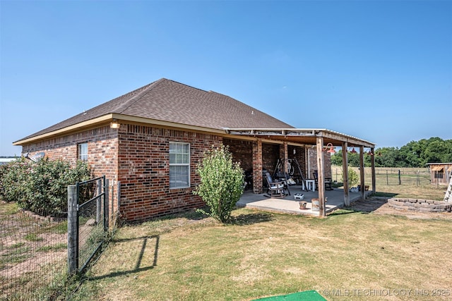 rear view of house featuring a yard, brick siding, a patio, and fence