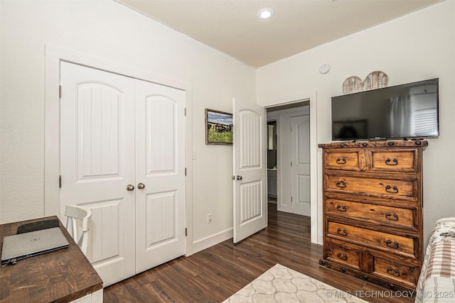 bedroom with a closet, dark wood finished floors, and baseboards