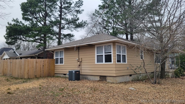 view of home's exterior with crawl space, fence, central AC unit, and roof with shingles