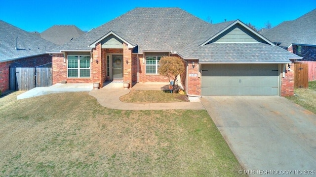 view of front facade with brick siding, fence, driveway, and an attached garage