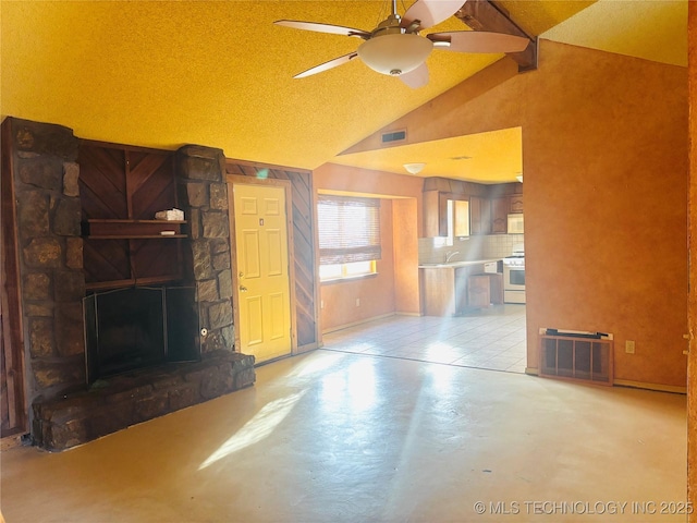 unfurnished living room featuring a fireplace, lofted ceiling, visible vents, a sink, and concrete floors