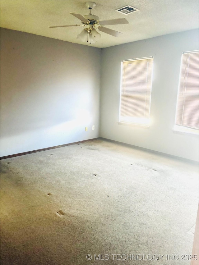 spare room with baseboards, visible vents, ceiling fan, a textured ceiling, and carpet flooring