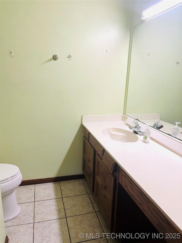 bathroom with toilet, tile patterned floors, baseboards, and vanity