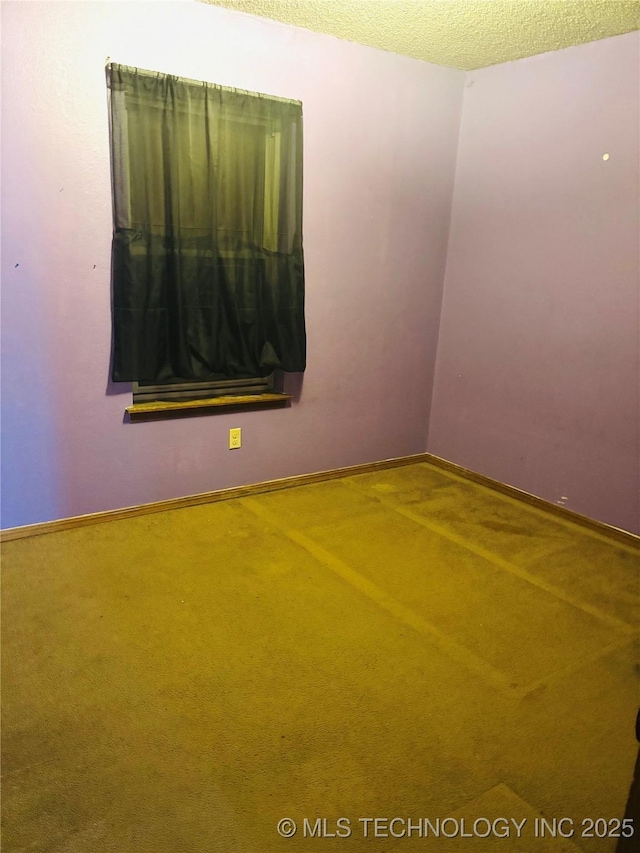 carpeted spare room featuring baseboards and a textured ceiling