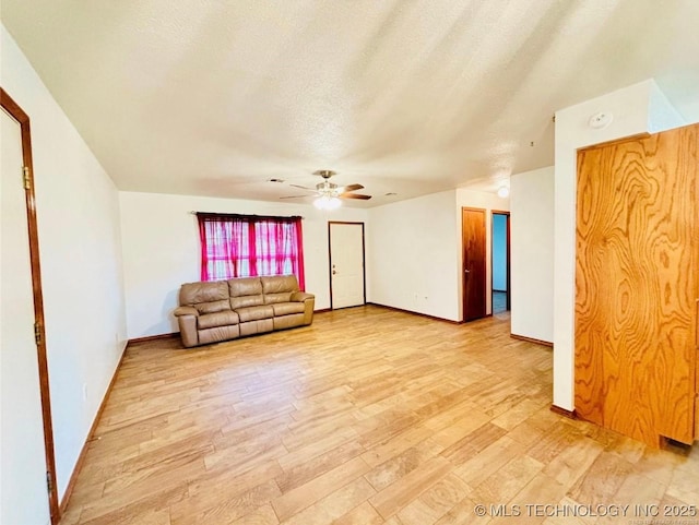 unfurnished living room featuring light wood-type flooring, baseboards, a ceiling fan, and a textured ceiling