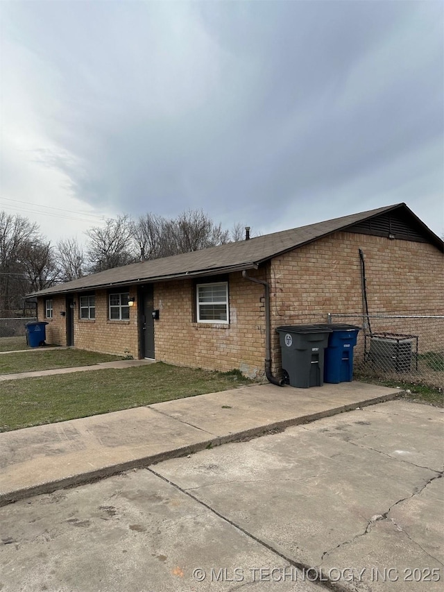 single story home featuring brick siding, a front yard, and fence