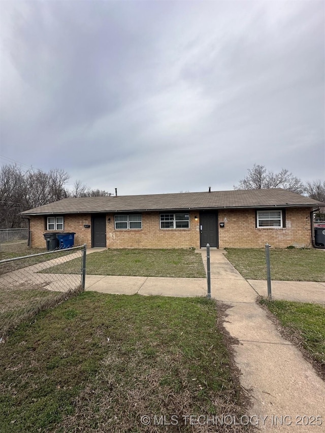 ranch-style home with brick siding, an attached garage, a front lawn, and fence