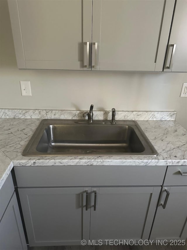 kitchen with a sink, light countertops, and gray cabinetry