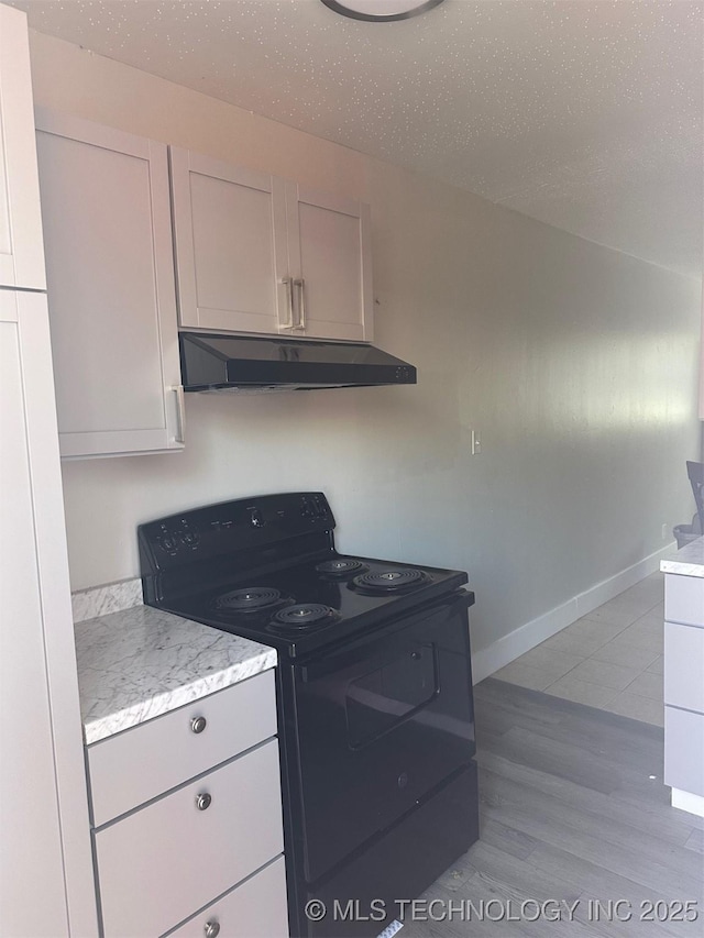 kitchen featuring baseboards, under cabinet range hood, light wood-style flooring, black electric range oven, and a textured ceiling