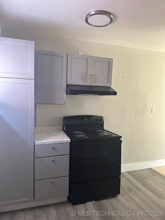 kitchen featuring black range with electric stovetop, light wood-style flooring, gray cabinetry, under cabinet range hood, and baseboards